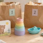 Board book, pastel stacking cups, a bath boat and toddler socks beside numbered paper gift bags.